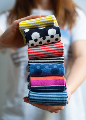 woman holding stack of brightly colored organic cotton socks