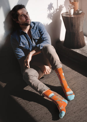 man sitting in the sunshine wearing a pair of western themed organic cotton socks