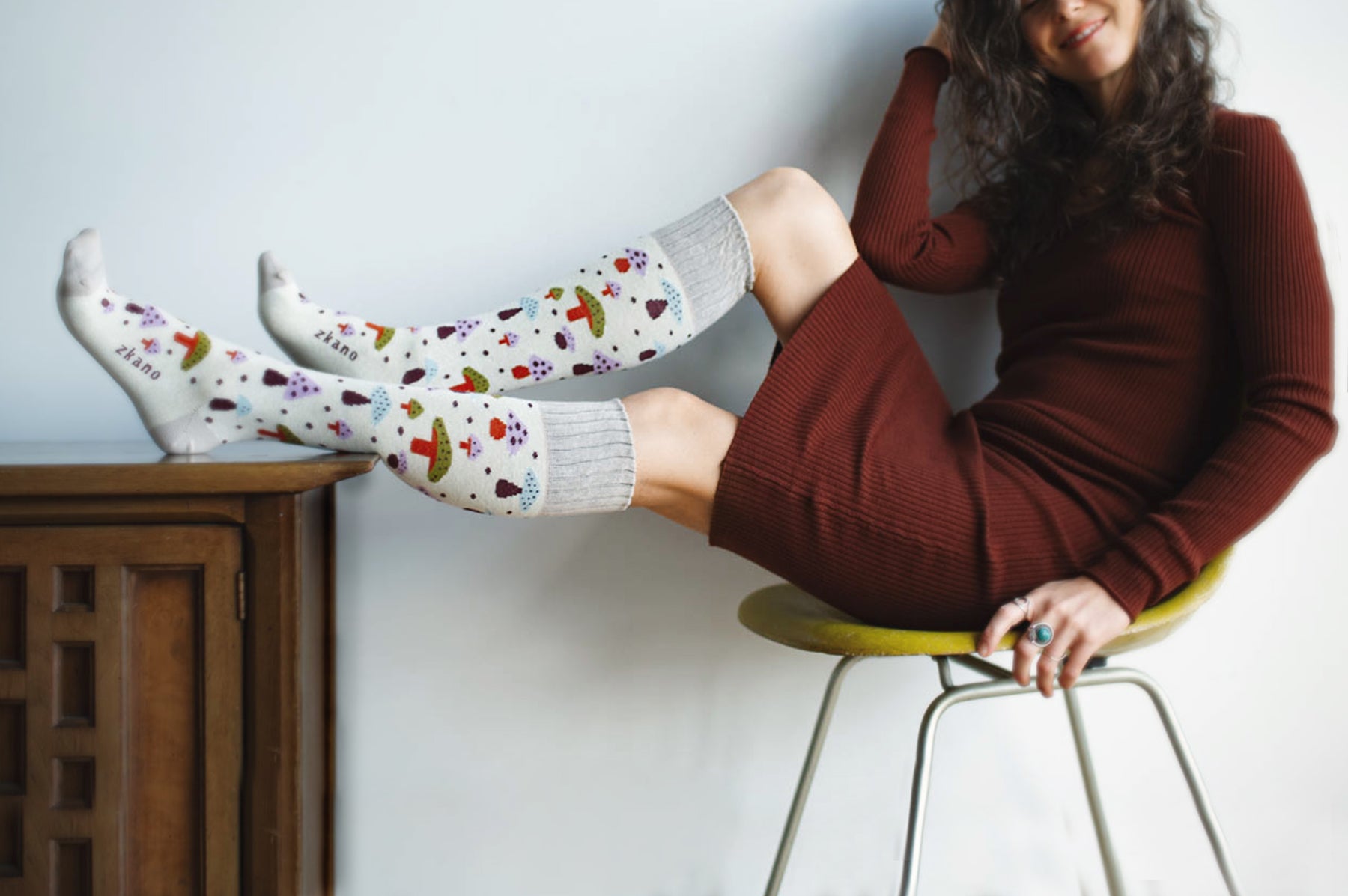 woman lounging in a chair wearing vivid mushroom patterned organic cotton knee socks