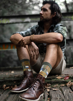 man sitting on an old bridge wearing patterned organic cotton socks