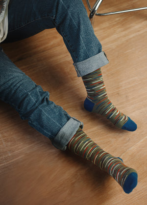 men's broken stripe crew sock worn by model wearing cuffed jeans and sitting on a wood floor