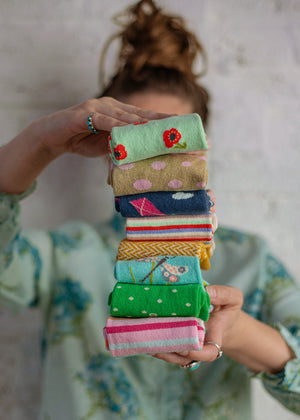 woman holding a stack of brightly colored, folded organic cotton socks