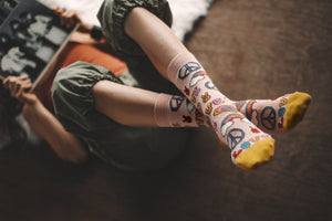woman holding a vintage record and wearing patterned organic cotton socks that say peace and love