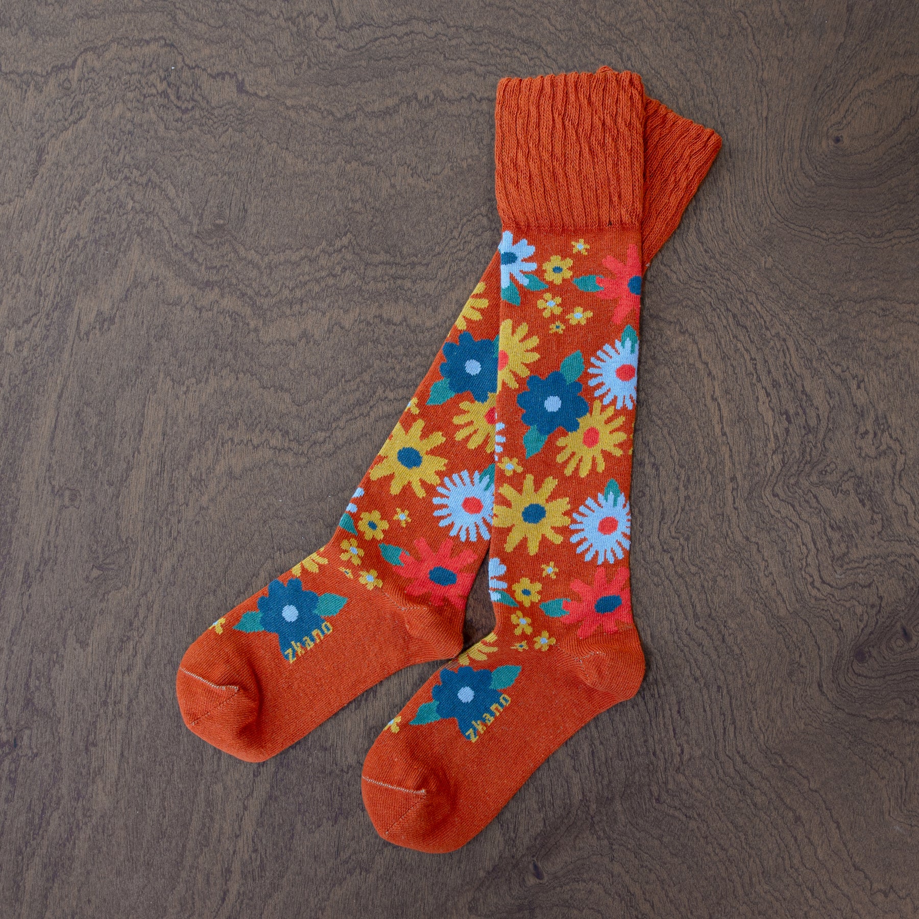 vivid floral organic cotton knee sock laying on a wooden surface