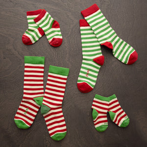 stripey kids and adult holiday socks laying on a wooden surface