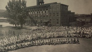 Black and white historic photo of a large group of workers outside a sock mill in the 1900's